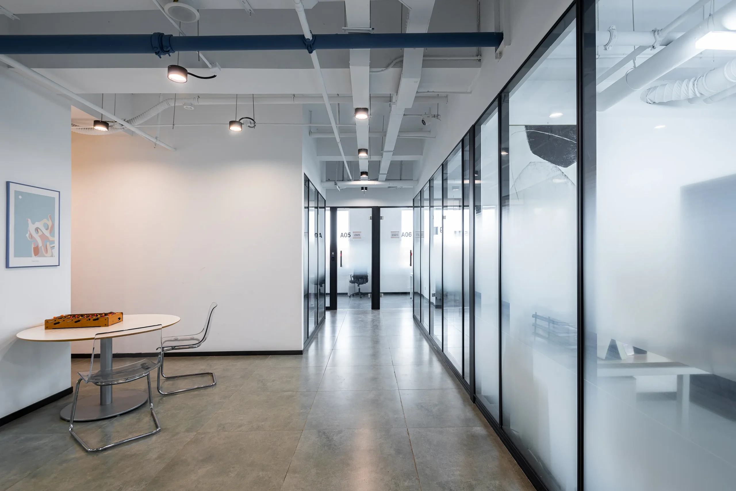 Aluminum framed glass partition wall in coworking office corridor with industrial-style ceiling