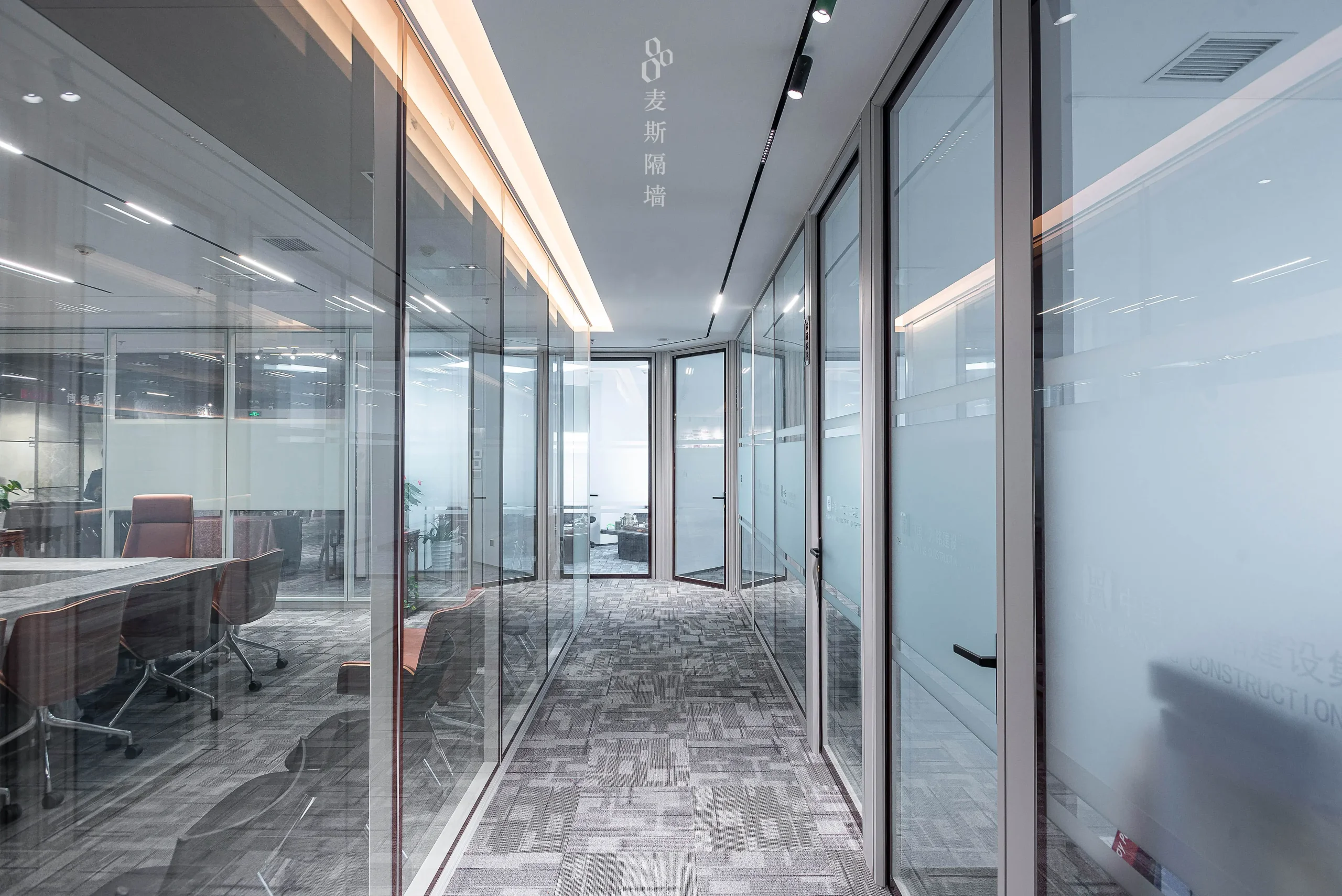 Office partition systems in a hidden-frame configuration — full-height glass corridor walls with slim frames and frosted branding bands in a corporate office