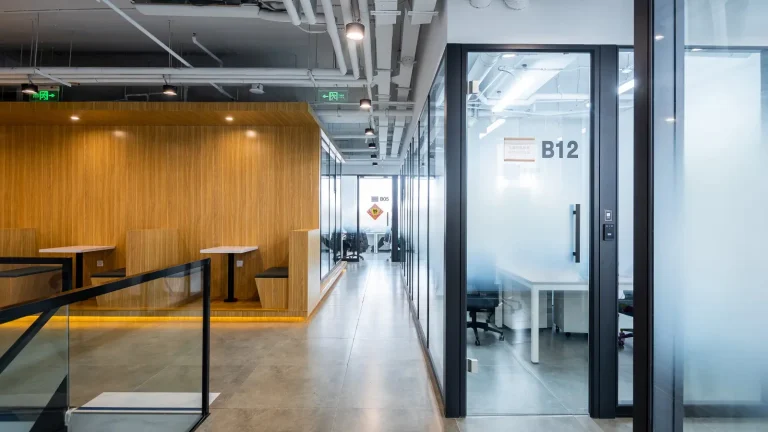 Aluminum framed glass partition private office pod with frosted door in coworking hallway (Blue Whale SOHO project)