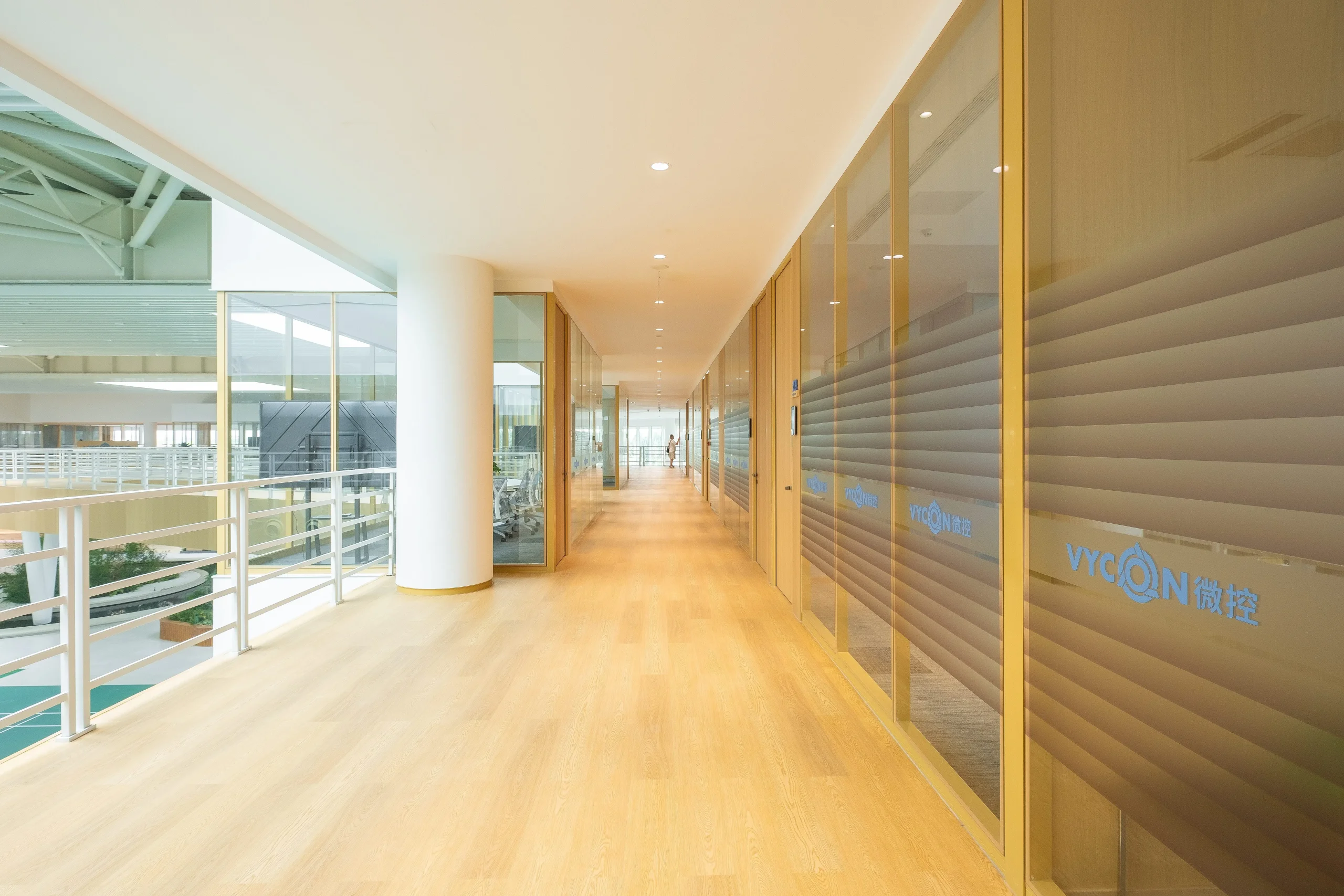 LEED glass partition with aluminium frames along a sunlit office corridor, letting daylight reach the interior