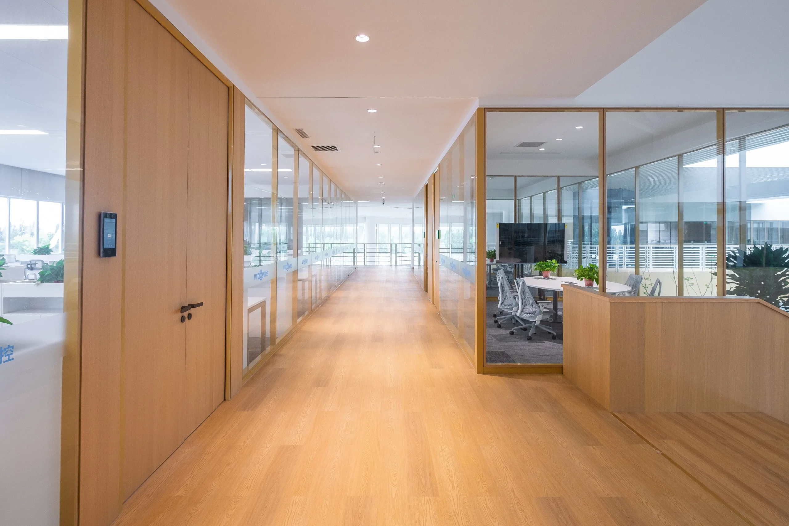 Wood office door finishes coordinated with an aluminium framed glass partition along an office corridor