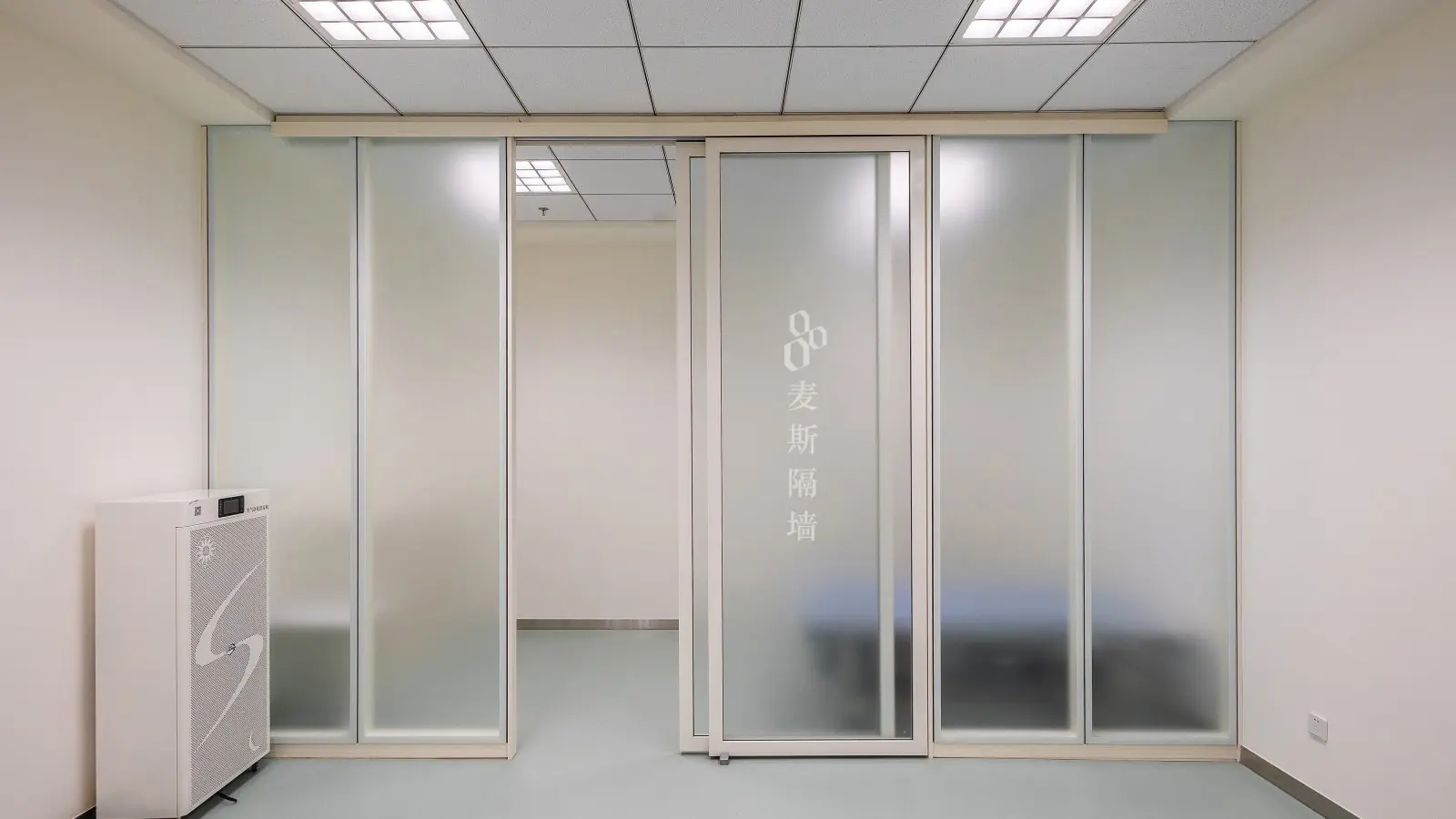 Partition door in sliding format, frosted glass panels on a ceiling-mounted concealed track with one leaf slid open