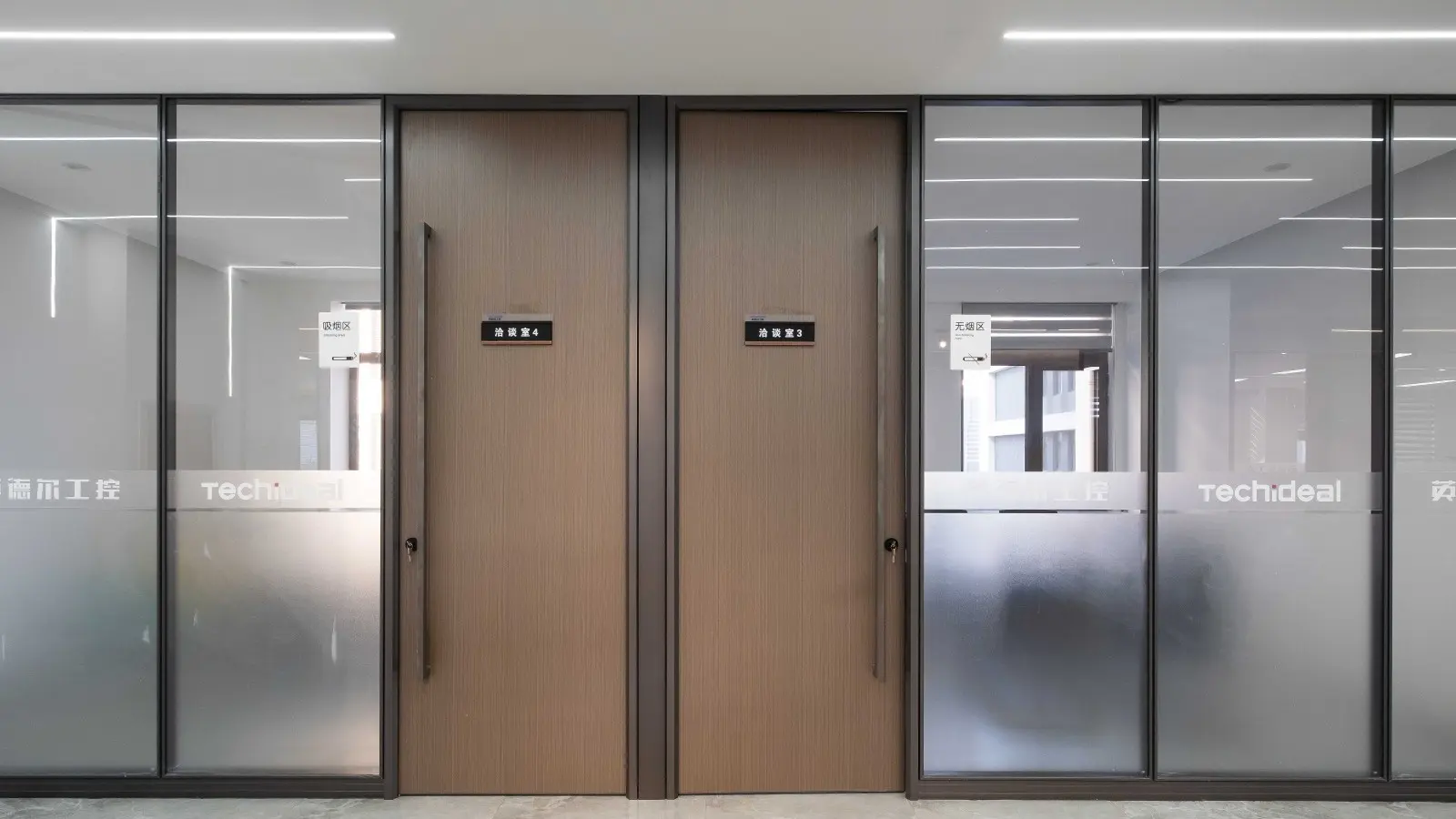 Wood office door pair with a dark veneer finish set into a frosted glass partition for meeting rooms